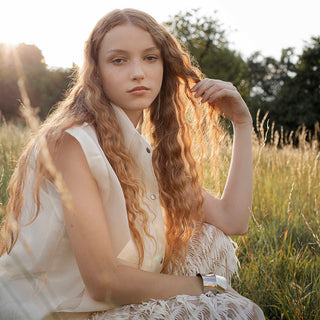 model with long red hair, a beige vest and a long skirt with fringes