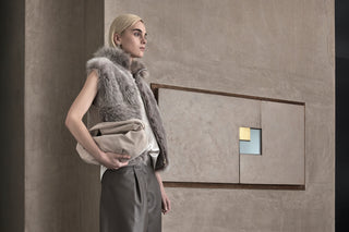 Woman wearing a sleeveless fur vest and leather bermuda shorts, holding the Luna bag in her hand